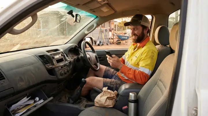 A tradie sitting in his ute taking a call on his mobile